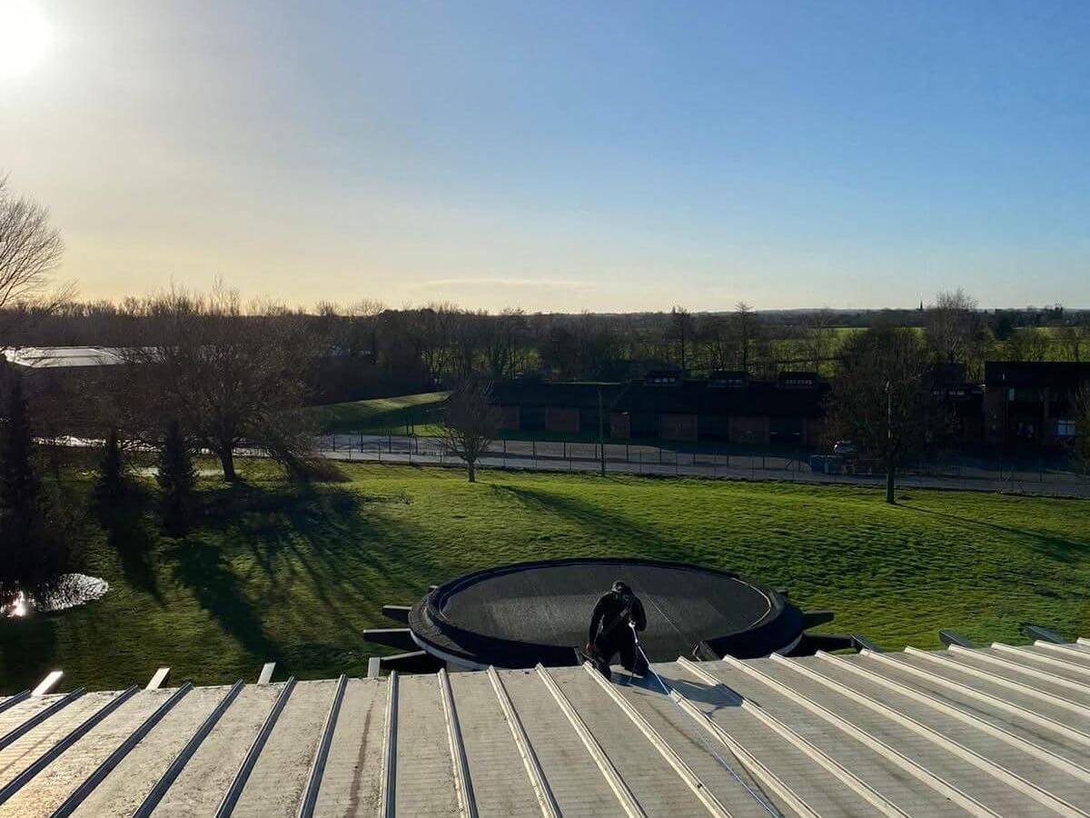 TLC Window Cleaning operative carrying out commercial roof cleaning on a large industrial building in Suffolk