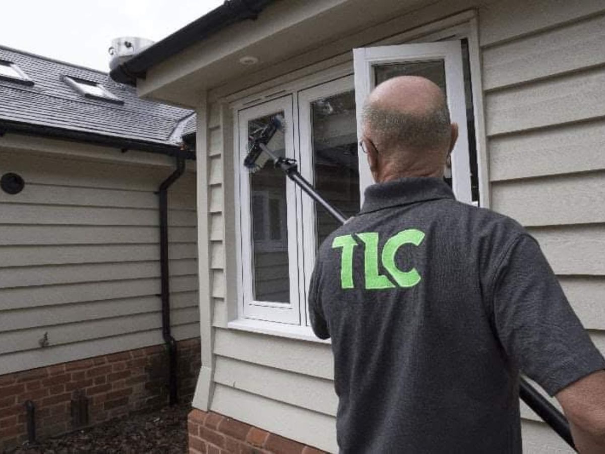 TLC window cleaning technician cleaning the windows of a holiday let property in Suffolk using a purified water system.