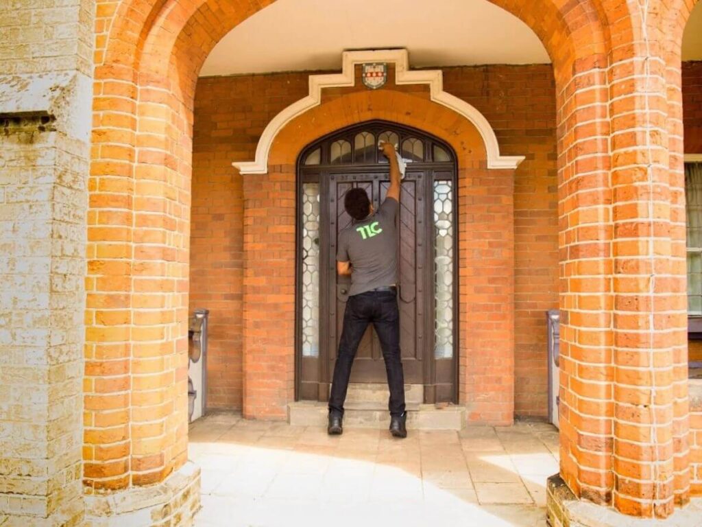Window cleaner cleaning glass around a residential entrance and brick archway