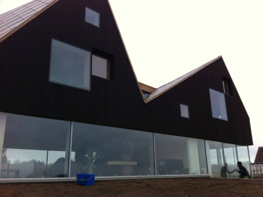 Modern residential property with floor-to-ceiling glass windows being professionally cleaned