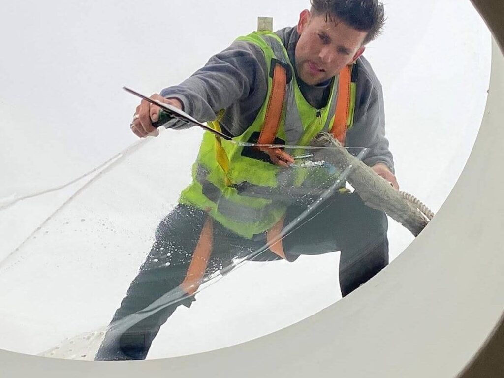 Professional window cleaner cleaning large glass window using traditional hand cleaning methods