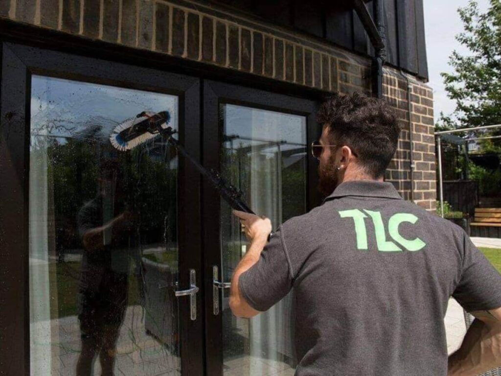 TLC Window Cleaning Technician cleaning exterior glass doors at a residential property.