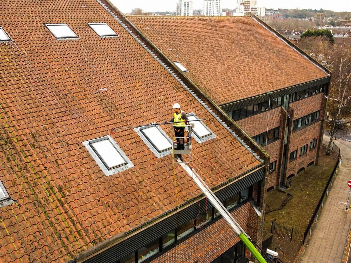 Commercial window cleaning technician using a MEWP to safely access high-level windows on a commercial building.