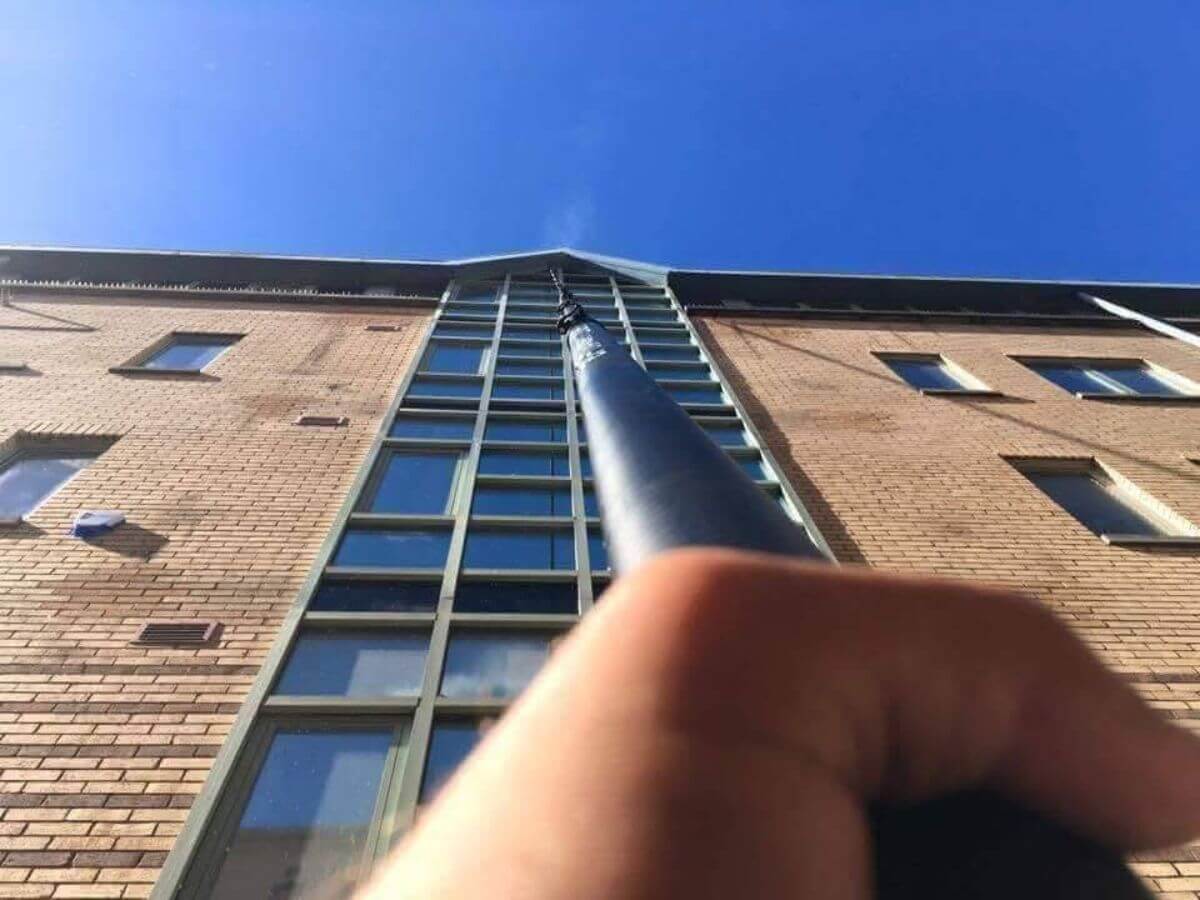 Commercial window cleaning using a water-fed pole system to clean high-level office windows safely from the ground.