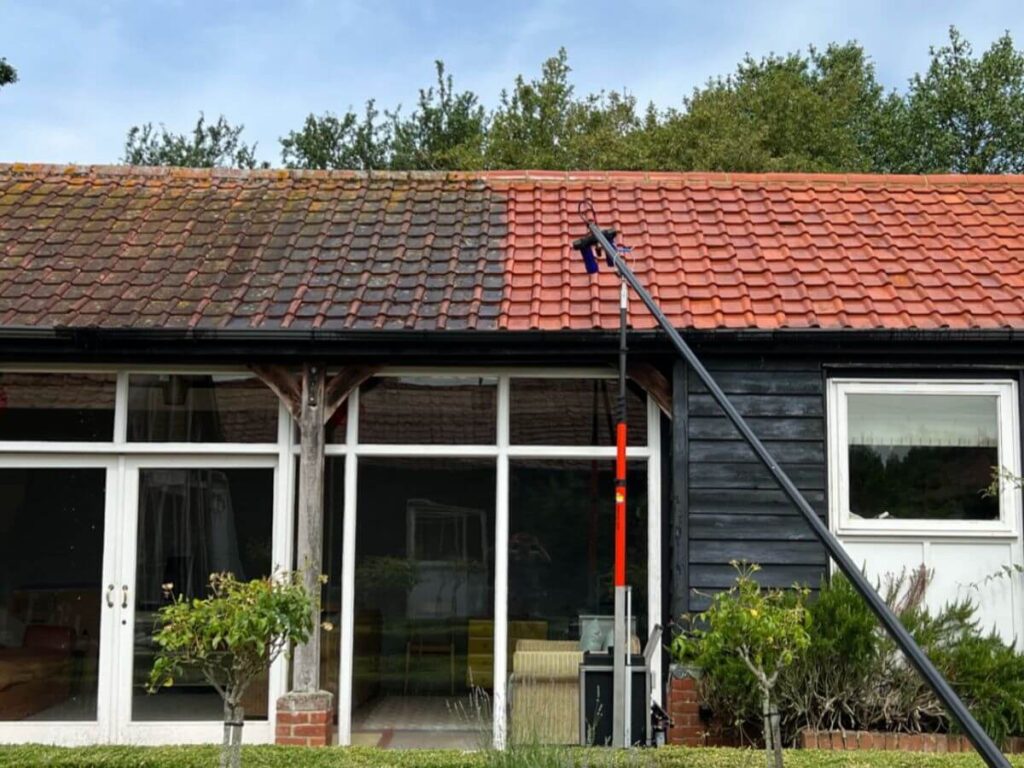 Red tiled roof half cleaned, showing bright clean tiles beside moss-covered and weathered tiles.